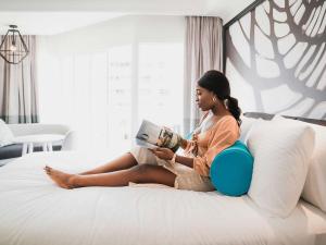 eine Frau, die auf einem Bett sitzt und ein Buch liest in der Unterkunft Pullman Cairns International in Cairns