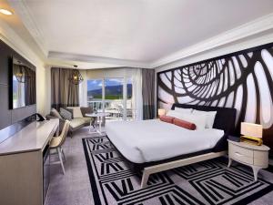 a hotel room with a large bed and a desk at Pullman Cairns International in Cairns