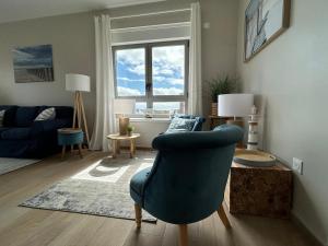 ein Wohnzimmer mit einem blauen Stuhl und einem Sofa in der Unterkunft Les Terrasses du Phare, vue mer, 100m plage, pkg, terrasses, accès PMR in Berck-sur-Mer + 31 Fotos