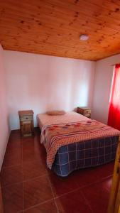 a bedroom with a bed and a wooden ceiling at Paihuen in Villa Quillinzo