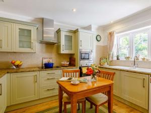a kitchen with white cabinets and a wooden table at 2 Bed in Bridport 88614 in Chideock