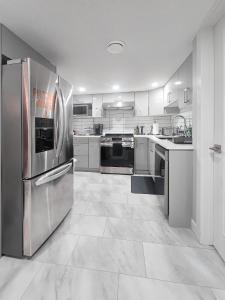 cocina grande con electrodomésticos de acero inoxidable y armarios blancos en Entire Superior 2-bedroom private suite, en Edmonton