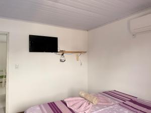 a bedroom with a bed and a tv on the wall at Da Silva Chalé in Santa Lídia