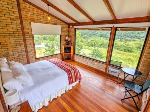 a bedroom with a bed and a table and some windows at Cabañas Las Nubes in Baeza