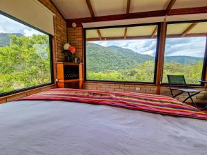a bedroom with a large bed and large windows at Cabañas Las Nubes in Baeza