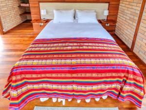 a bed with a colorful blanket on top of it at Cabañas Las Nubes in Baeza +65 photos