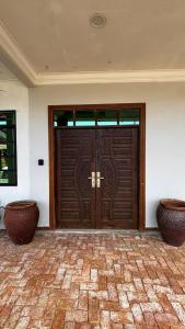 a large wooden door with two vases in front of it at Cwa Homestay in Kampong Molek +1 photo