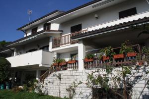 a white house with potted plants on the balcony at B&B Villa Inn in Trieste