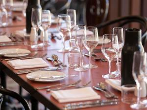 a table with wine glasses and silverware on it at The Sebel Kiama in Kiama