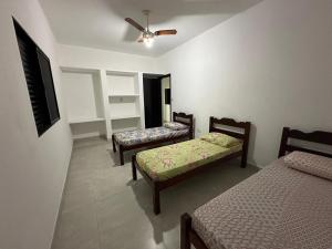 Zimmer mit 3 Betten und einem Deckenventilator in der Unterkunft Casa, Boqueirão Norte em Ilha Comprida- SP in Ilha Comprida