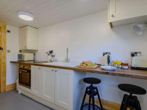 a kitchen with white cabinets and two bar stools at 1 Bed in Conwy 79464 in Conwy
