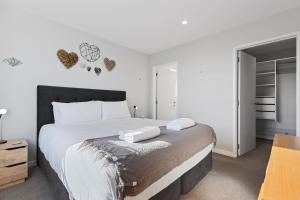 a bedroom with a large bed with white sheets at Papamoa Beach Retreat in Tauranga
