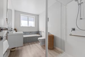 a bathroom with a shower and a toilet and a sink at Papamoa Beach Retreat in Tauranga +13 photos
