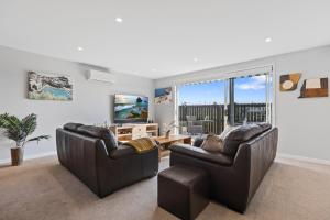 a living room with two leather chairs and a television at Papamoa Beach Retreat in Tauranga