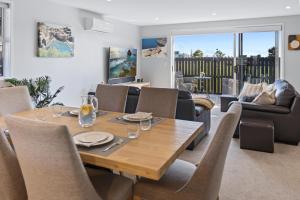 a dining room and living room with a wooden table and chairs at Papamoa Beach Retreat in Tauranga