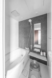 a white bathroom with a tub and a mirror at The Arklune in Sapporo +64 photos
