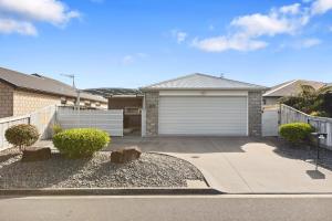 a house with a garage and a driveway at Papamoa Beach Retreat in Tauranga