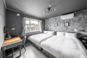 a bedroom with a large bed and a desk and a window at The Arklune in Sapporo