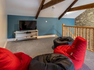 a living room with two red chairs and a flat screen tv at 4 Bed in New Quay 78801 in Llandyssiliogogo