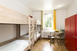 Pokój z 2 łóżkami piętrowymi i stołem w obiekcie Jugendherberge Bonn w mieście Bonn