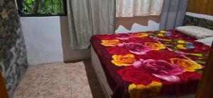 Una cama con una manta con flores. en La casa del tío, en San Juan La Laguna