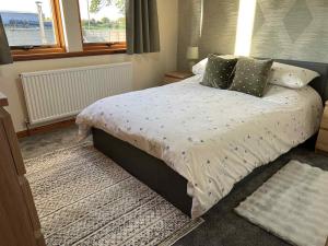 a bedroom with a bed with a white comforter and a window at 3 Bed in Port William 87541 in Mochrum