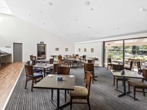 une salle à manger avec tables, chaises et fenêtres dans l'établissement ibis Styles Canberra Eagle Hawk, à Canberra