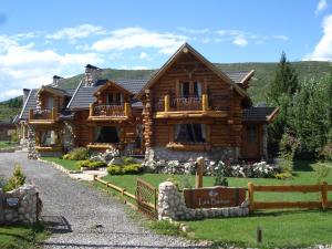 uma cabana de madeira com uma cerca em frente em Las Baitas em San Carlos de Bariloche