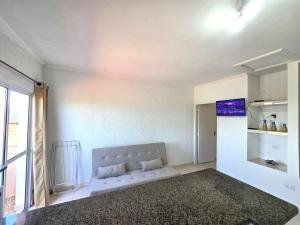 a bedroom with a white couch and a window at Pousada Mar e Luz in Ilha Comprida