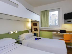 une chambre avec deux lits et un bureau avec un ordinateur dans l'établissement ibis budget Porto Alegre - Super Econômico, à Porto Alegre