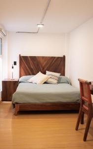 a bed with a wooden headboard in a bedroom at Calle y Número, López Cotilla in Guadalajara