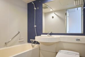 a bathroom with a sink and a toilet and a mirror at Hotel Villa Fontaine Tokyo-Hamamatsucho in Tokyo