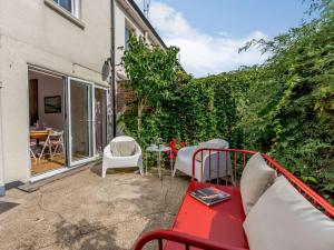 イーストボーンにある3 Bed in Eastbourne 83924の赤いベンチと緑の生垣のあるパティオ