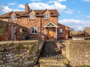 una vieja casa de ladrillo con un camino de piedra delante de ella en 4 Bed in Blakeney 90589, en Awre