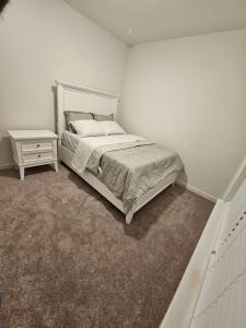 a white bedroom with a bed and a night stand at Talia Heaven in Mesquite