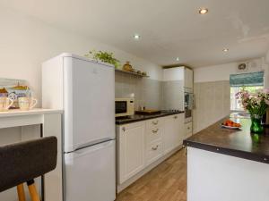 a kitchen with white cabinets and a white refrigerator at 2 Bed in Nefyn 44492 in Nefyn