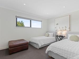 a white bedroom with two beds and a window at Time Out on Flinders in Indented Head