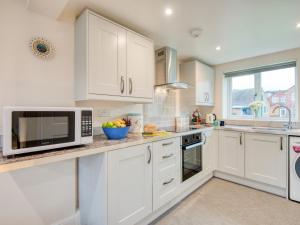 a kitchen with white cabinets and a microwave at 1 bed property in Godshill 77796 in Downton +4 photos