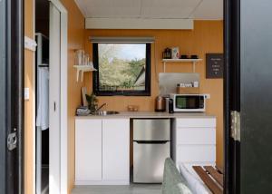 a small kitchen with a sink and a microwave at Forest Farm Tiny House by Tiny Away in Tauranga