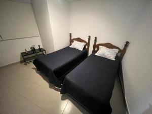 two beds with black sheets in a room at ANTAREs in Sanctórum