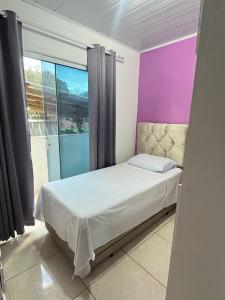 a bedroom with a bed and a purple wall at Casa 3 quartos Canasvieiras e ingleses in Florianópolis