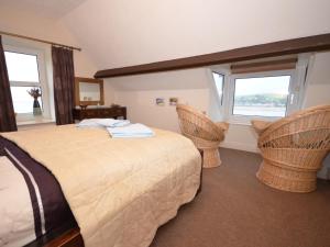 a bedroom with a bed and two chairs and two windows at 2 Bed in Appledore GABLE in Appledore
