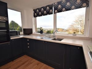 a kitchen with black cabinets and a large window at 2 Bed in Instow SANDB in Instow