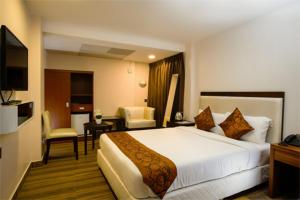 Pokój hotelowy z dużym białym łóżkiem i biurkiem w obiekcie KGA Elite Continental Hotel w mieście Thiruvalla