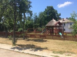 a wooden fence with a playground in front of a house at Guest House Salcia in Maliuc