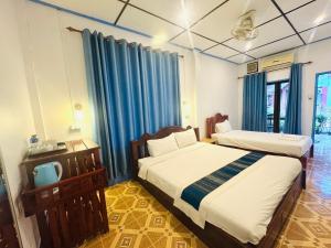 two beds in a room with blue curtains at Le Jardin 2 Organique Guesthouse Vang Vieng in Vang Vieng