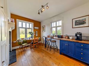 a kitchen with blue cabinets and a table with chairs at 4 Bed in Fairbourne 42772 in Fairbourne