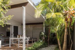 a patio with a table and chairs and palm trees at The Local House - Eco Stay, Byron Bay in Byron Bay
