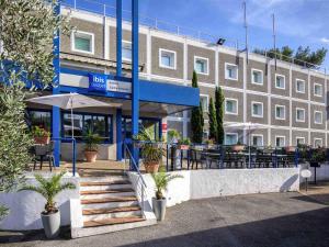 a building with a table and chairs in front of it at ibis budget Antibes Sophia Antipolis in Vallauris