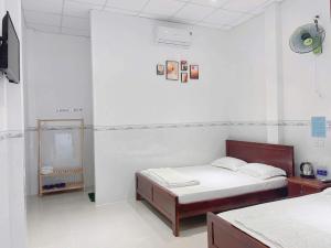 a white room with two beds and a clock on the wall at Nhà Nghỉ Bi Ti in Ấp Long Sơn